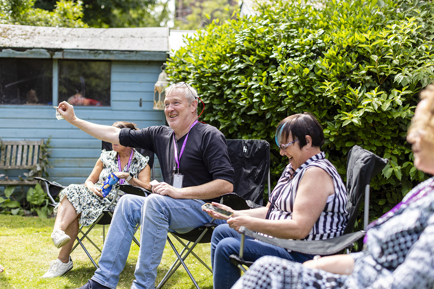 Supported living residents and staff enjoying garden activity photographed for housing association marketing imagery