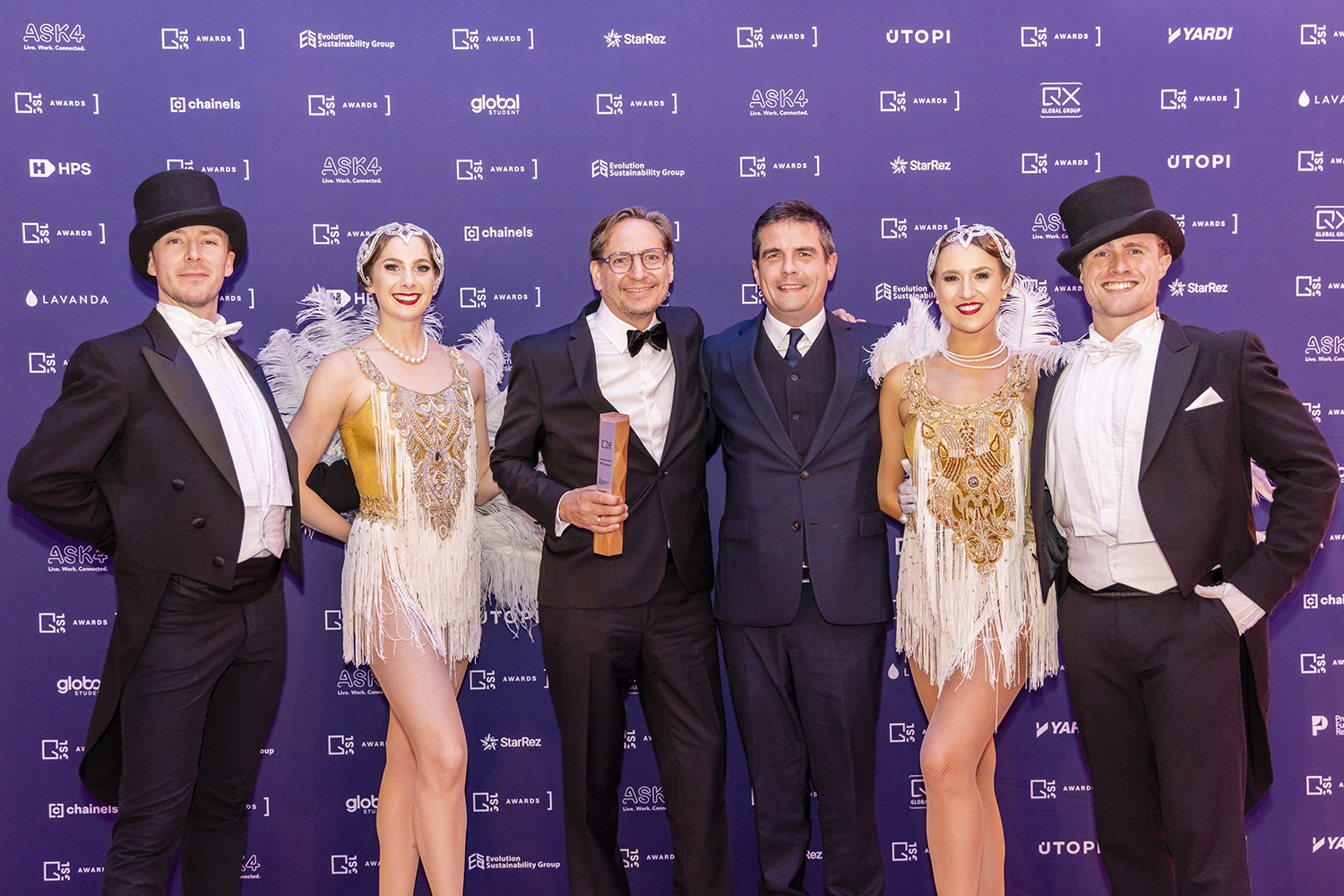 Formal group portrait of award winners at London event with branded backdrop